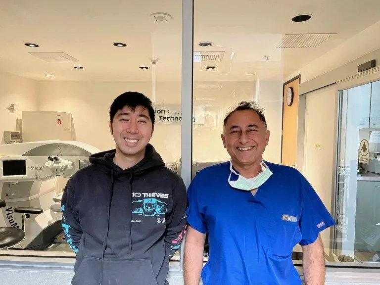 Dr. Khanna in blue scrubs standing with a patient in the laser suite