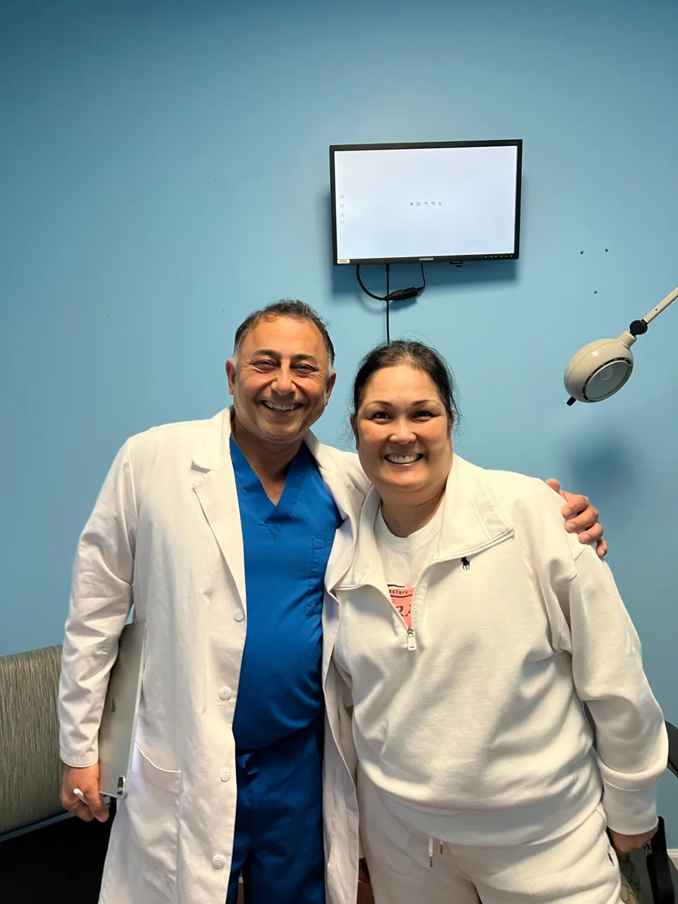 Dr. Khanna in a white coat standing with a smiling woman in an exam room