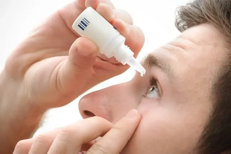 Patient putting in prescribed eye drops after laser vision correction